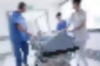Medical staff rushing patient on gurney through hospital hallway, emergency care relevant to personal injury cases