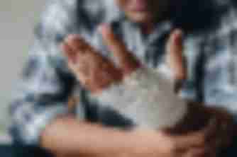 Man in plaid shirt holding his bandaged wrist after a personal injury accident