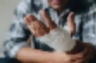 Man in plaid shirt holding his bandaged wrist after a personal injury accident